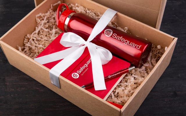 An opened gift box with a Safeguard water bottle, notepad, and pen.