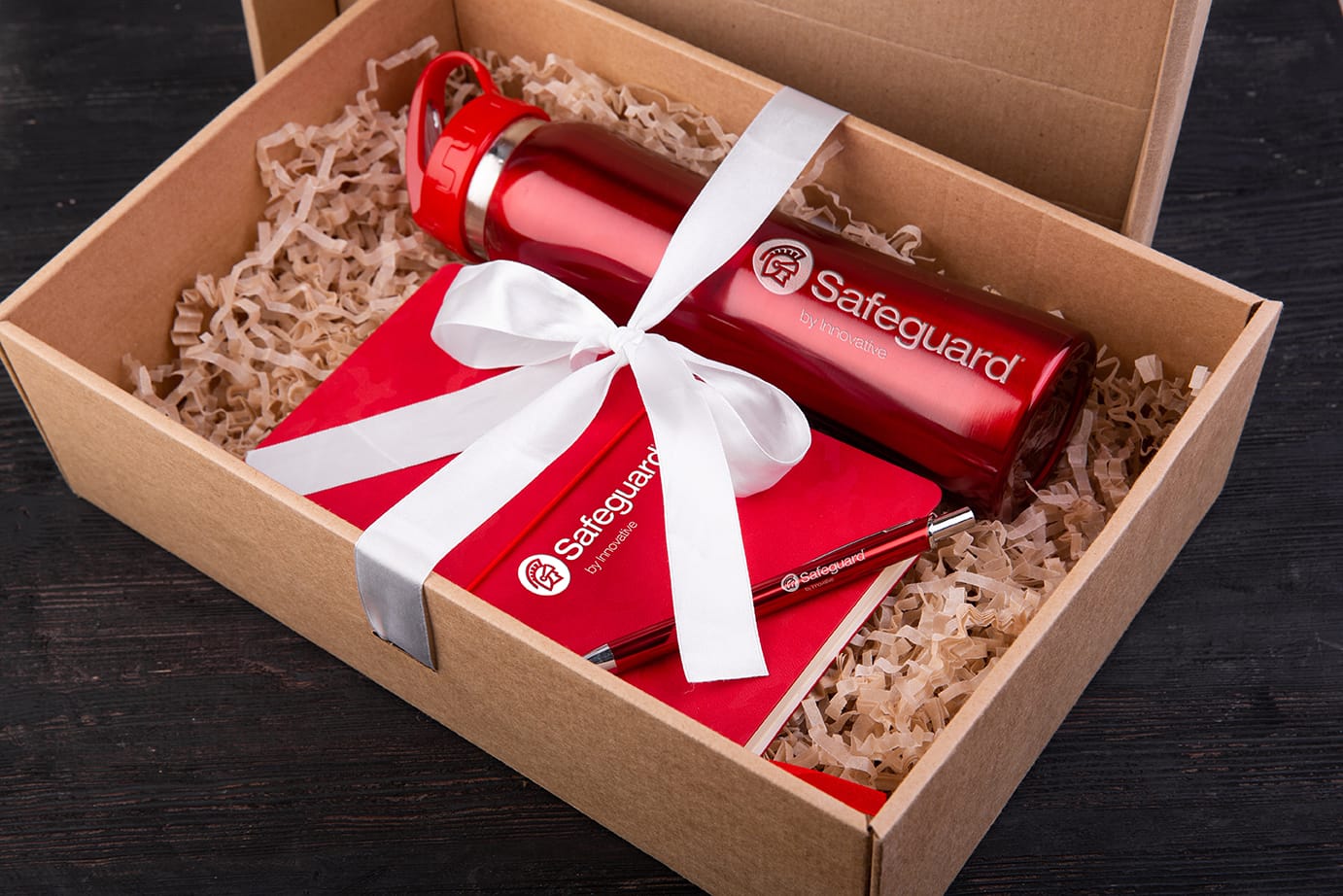 An opened gift box with a Safeguard water bottle, notepad, and pen.