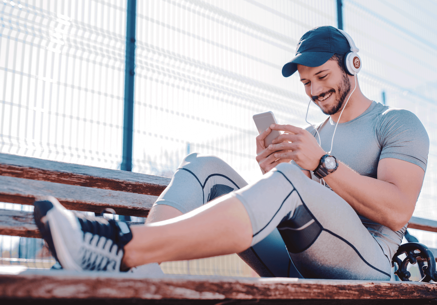 A man wearing athletic clothes smiles at his phone while wearing Safeguard by Innovative branded headphones.