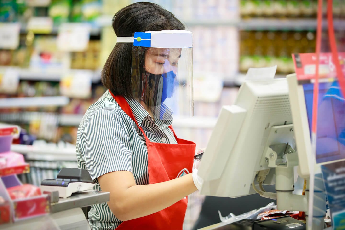 A grocery store worker wearing a mask and a face shield.