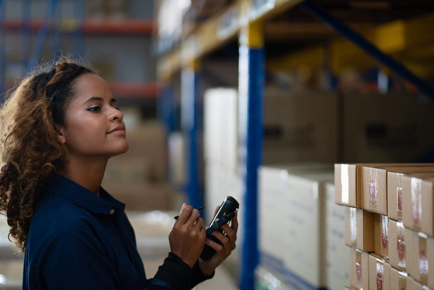 Woman employee checking packaging orders inside a warehouse.