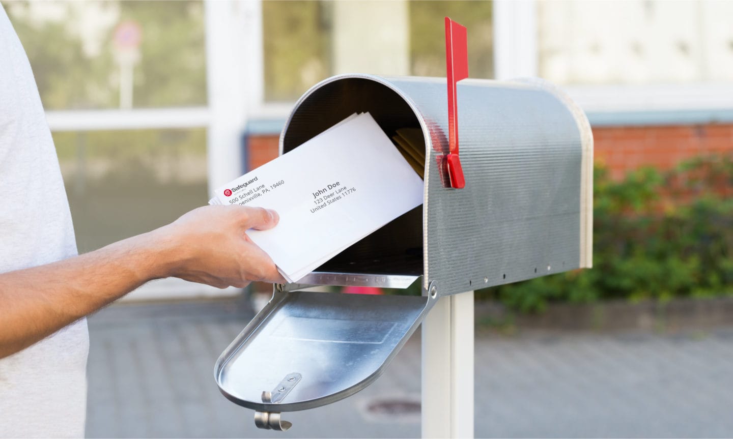 A hand putting letters into mailbox.