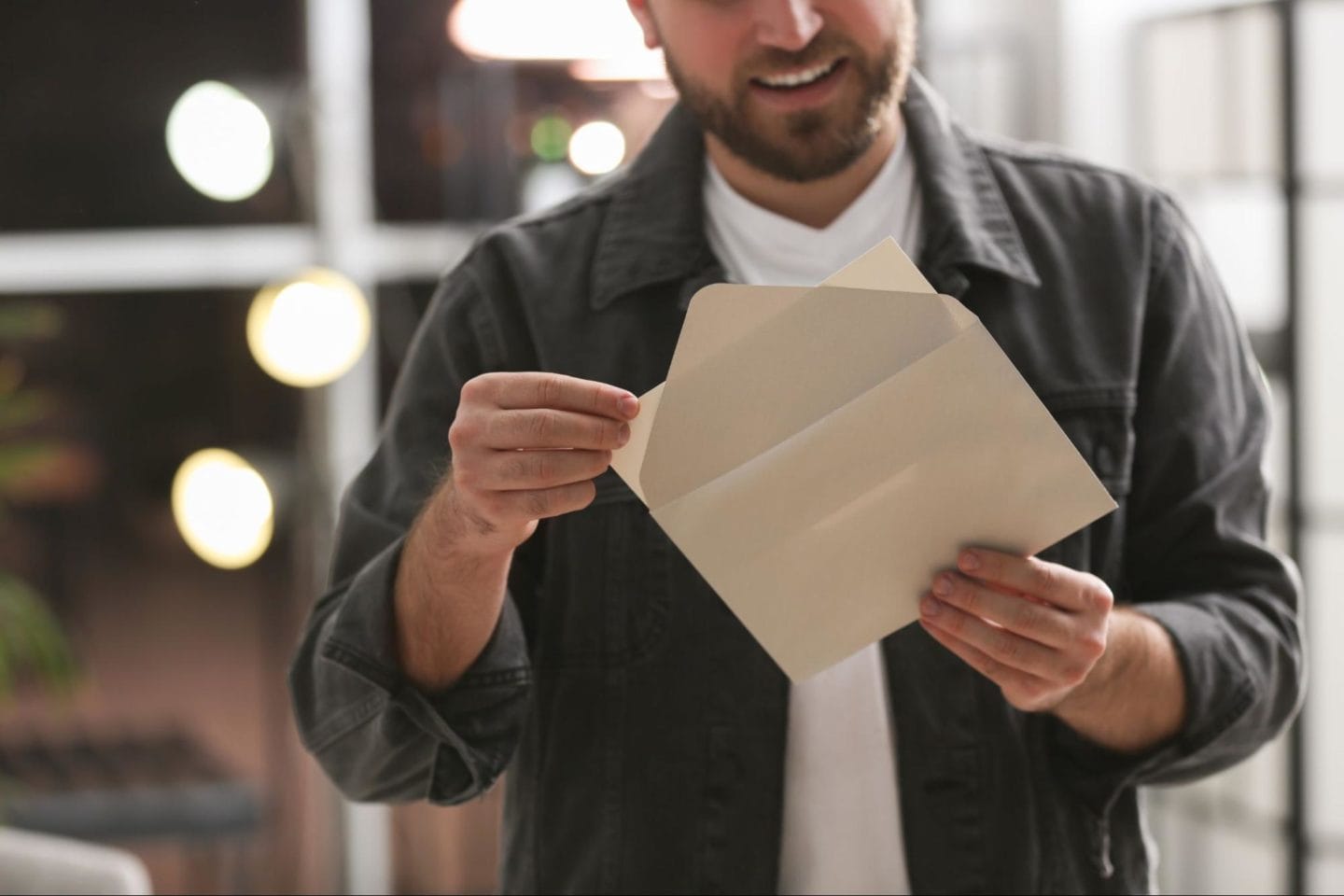 A picture of a man opening an envelope and taking out a letter.