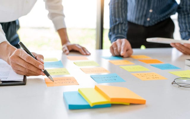 Business meeting collaboration using sticky notes lined up on a table.
