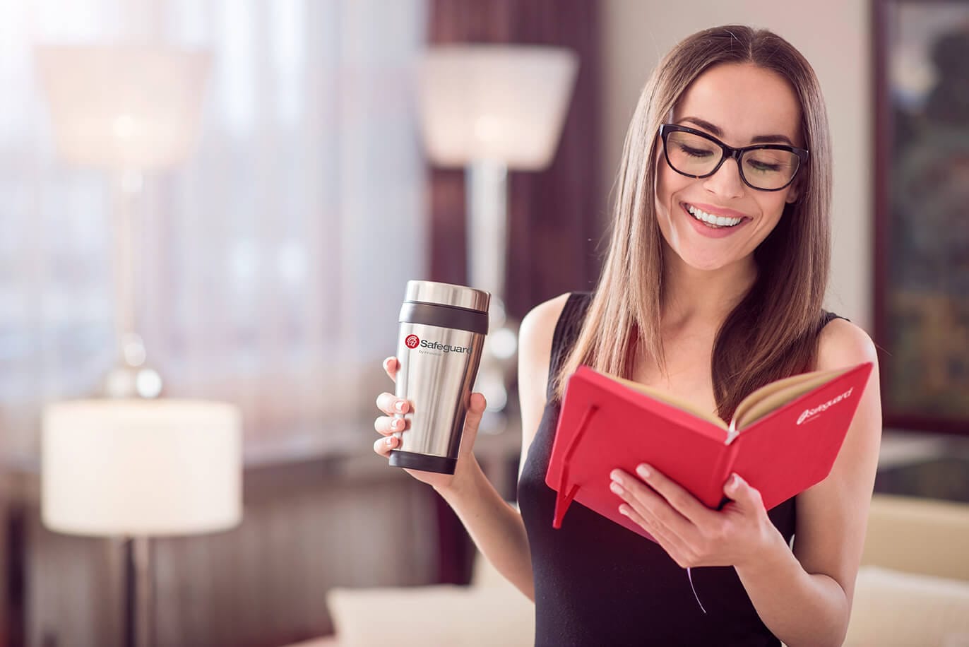 Smiling woman holding a Safeguard mug and notebook.