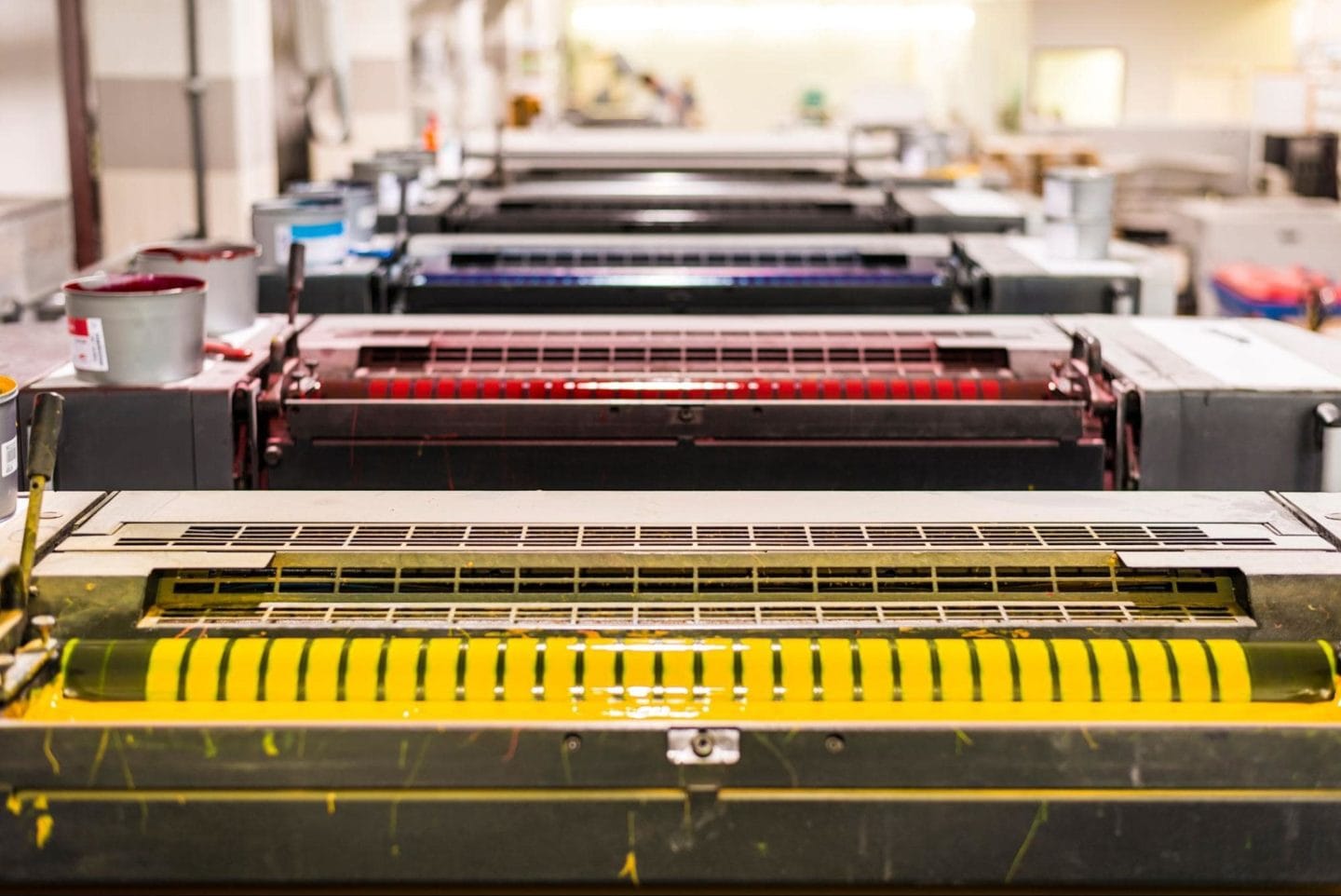 A picture of three offset printers, with yellow, red, and blue aesthetics.