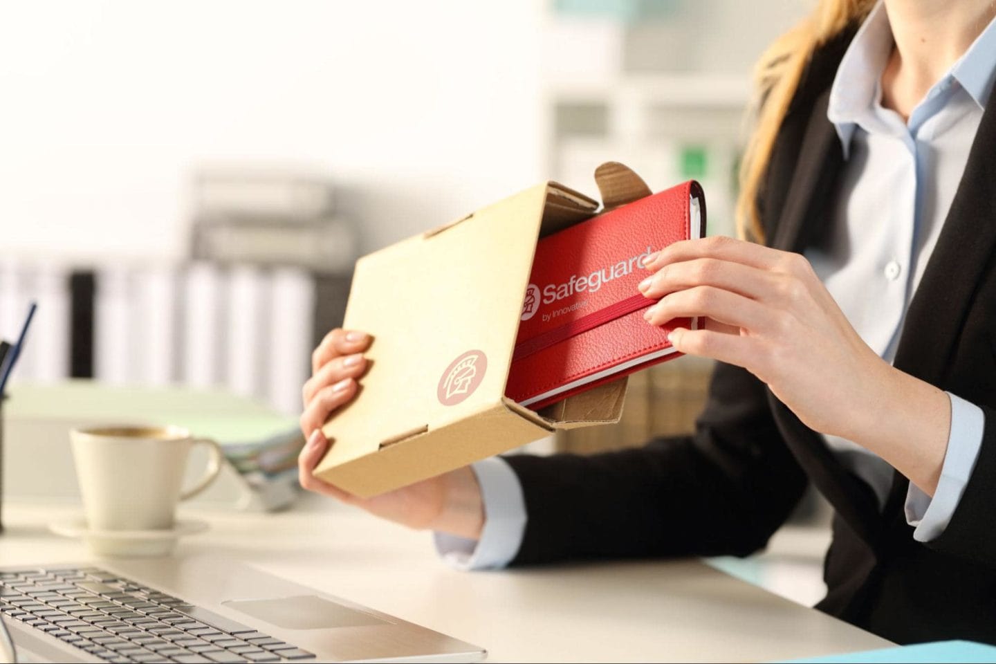 A business professional opening a package and pulling out a red notebook.