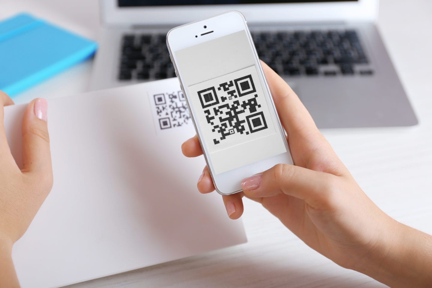 Hands holding a cell phone and scanning a QR code.