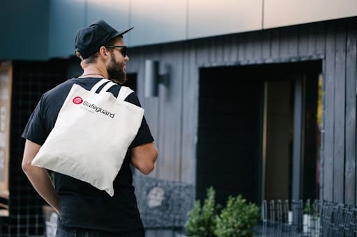 A man carrying a tote bag over his shoulder with the Safeguard by Innovative logo on it. 