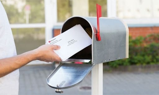 A person putting a couple letters in their mailbox.