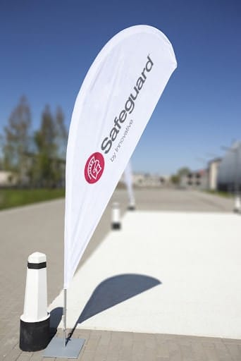A custom, outdoor, fabric flag sign in the shape of a quill with Safeguard by Innovative's logo on it. 